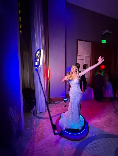 Bride dancing on a 360 video booth platform under purple lights
