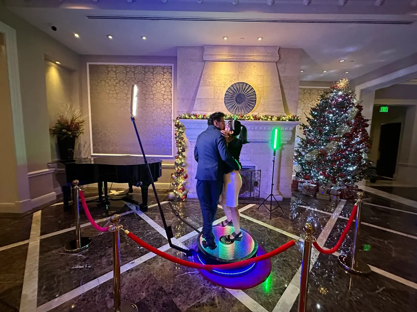 Couple kissing on a 360 video booth with velvet rope stanchions